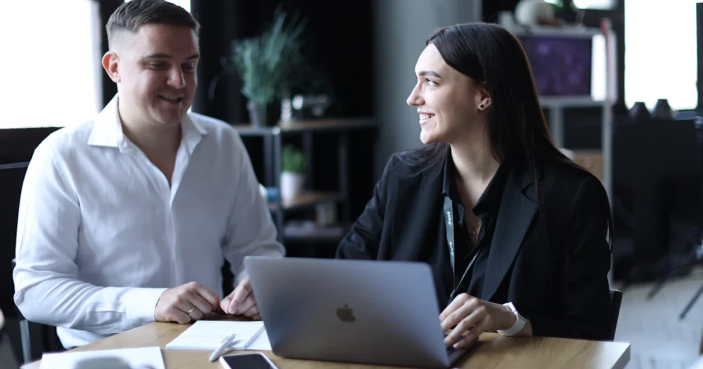 Två personer diskuterar och planerar arbete vid ett bord